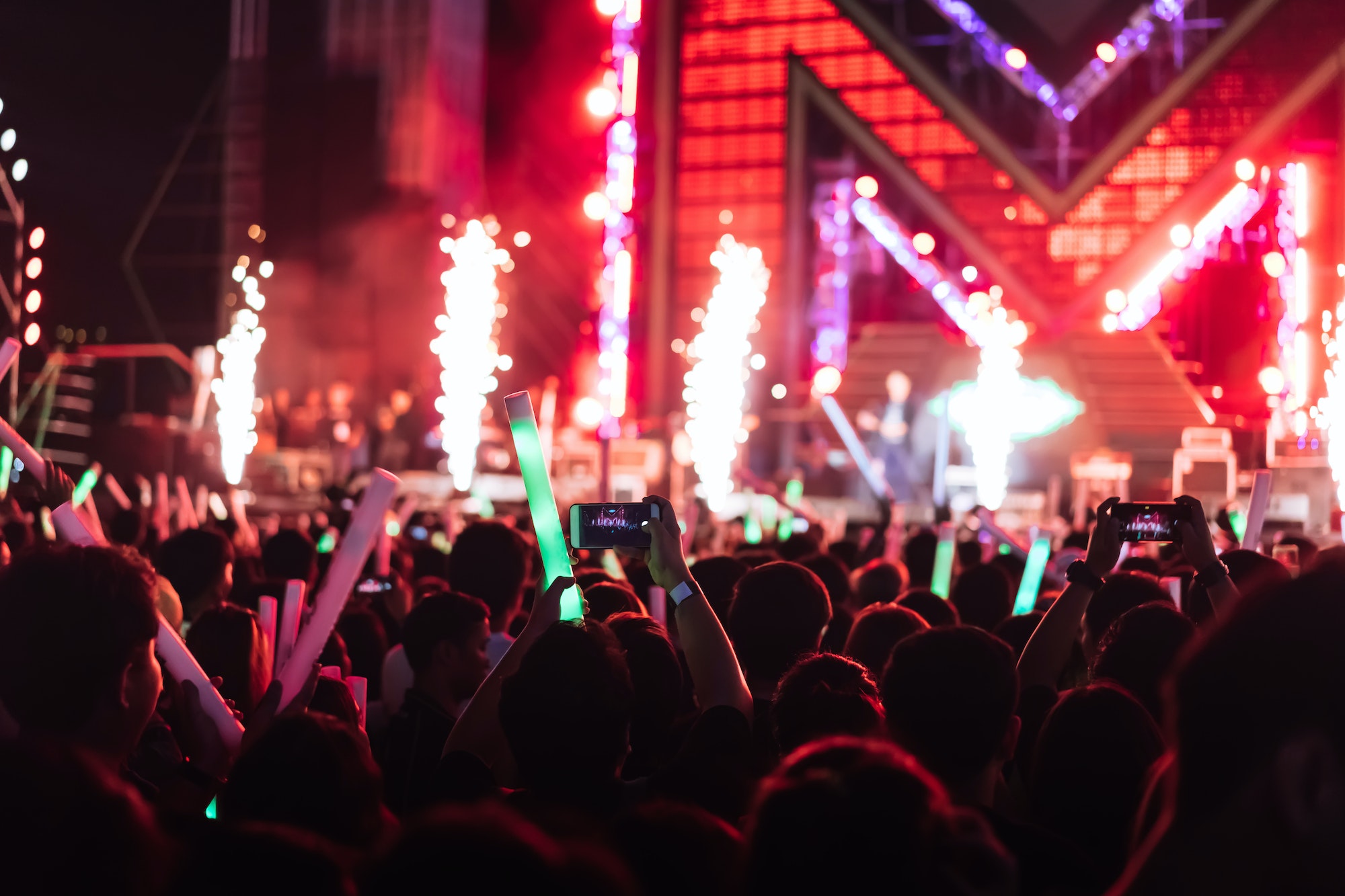 Crowd of concert stage lights and people fan audience silhouette raising hands or glow stick holding